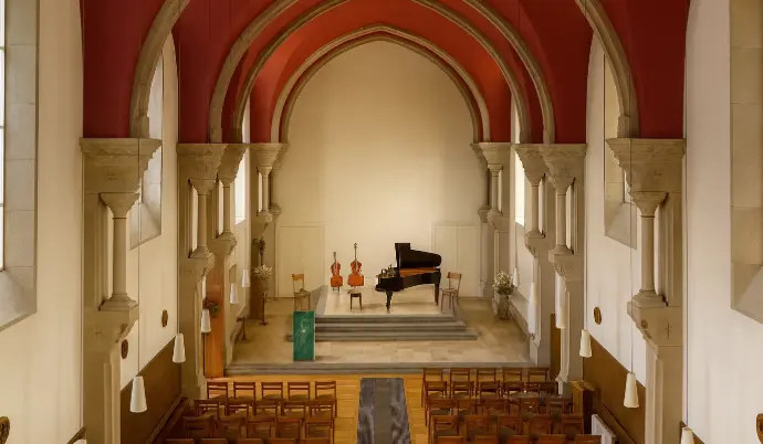 Scène de concert classique dans la chapelle du domaine, avec piano et instruments à cordes dans un cadre patrimonial lumineux à Besançon.