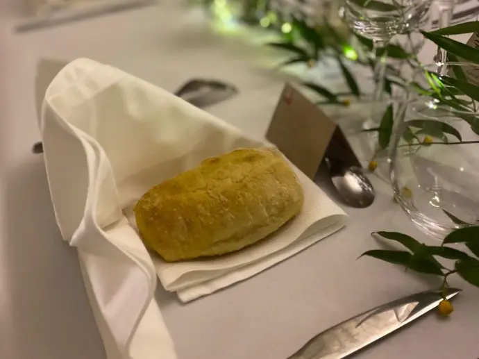 Pain individuel sur serviette blanche, sur une table dressée pour un repas de réception.
