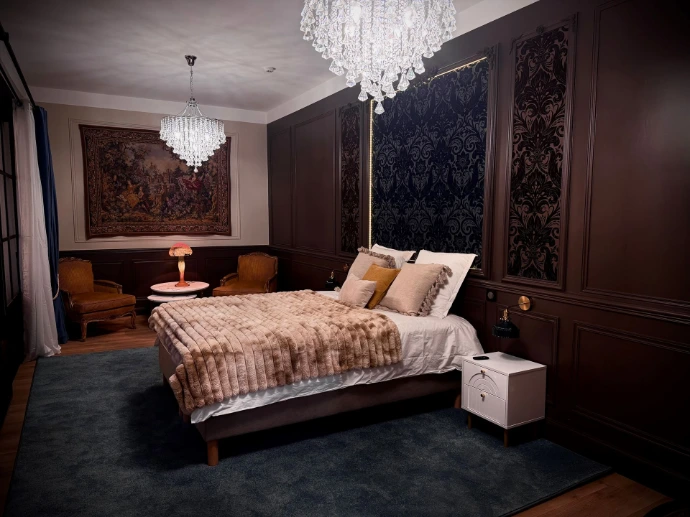 Grande chambre élégante avec lit double, boiseries sombres et lustres en cristal à L’Écrin du Monastère, près de Besançon.
