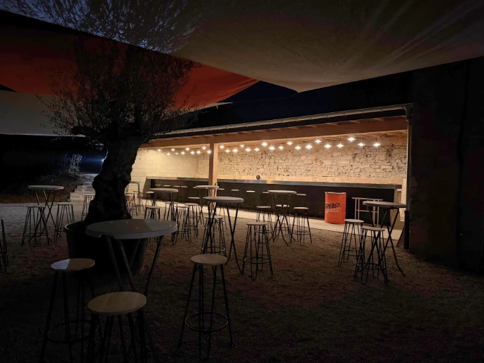 Espace bar extérieur éclairé en soirée, aménagé pour les réceptions et événements à L’Écrin du Monastère, près de Besançon.