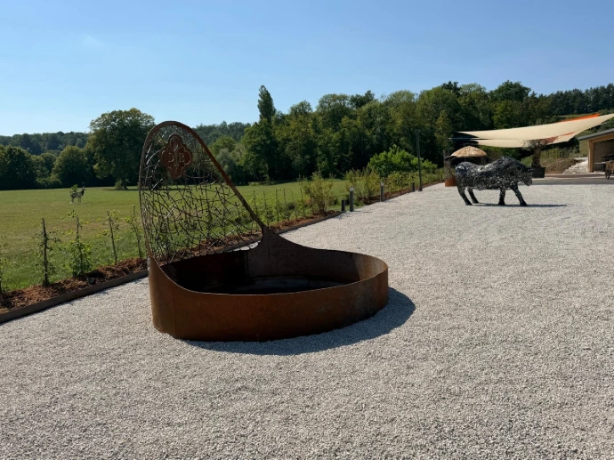 Terrasse extérieure du domaine avec sculptures contemporaines et vue sur le parc de L’Écrin du Monastère, en Bourgogne-Franche-Comté.