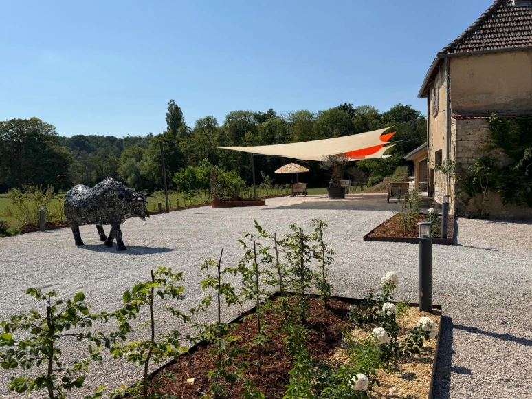 Terrasse extérieure du domaine avec sculpture contemporaine et espace bar aménagé au fond, à L’Écrin du Monastère, à Montferrand-le-Château.