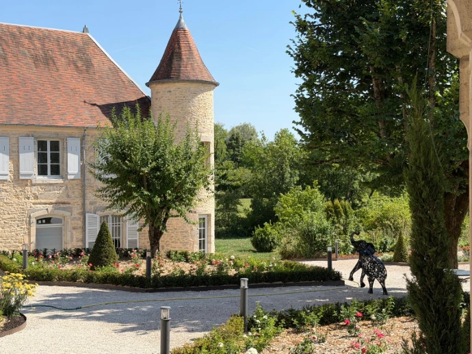 Vue du château et de sa tour en pierre au cœur des jardins de L’Écrin du Monastère.