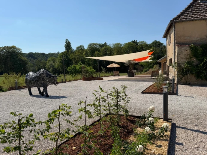 Terrasse extérieure du domaine avec sculpture contemporaine et espace bar aménagé au fond, à L’Écrin du Monastère, à Montferrand-le-Château.